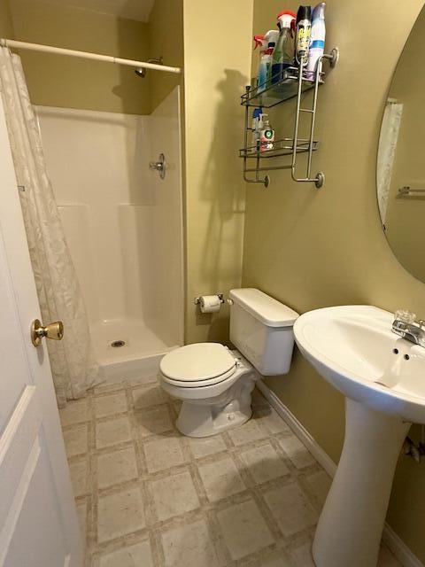 bathroom with a shower stall, tile patterned floors, and toilet