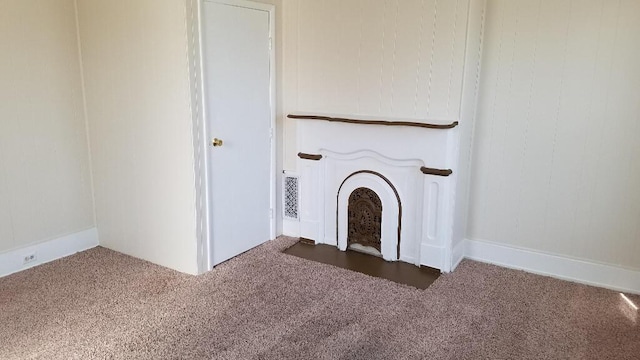 unfurnished living room with dark carpet and a fireplace with flush hearth