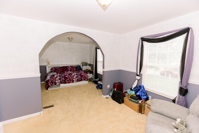 carpeted bedroom with arched walkways