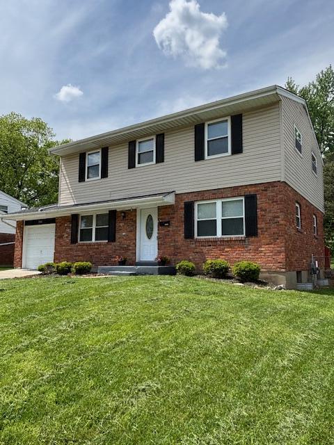 traditional home with a garage, a front lawn, and brick siding