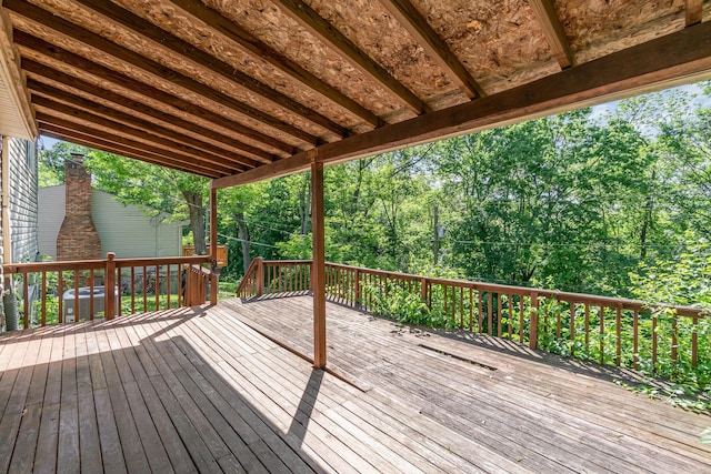 wooden deck featuring central air condition unit and view of wooded area