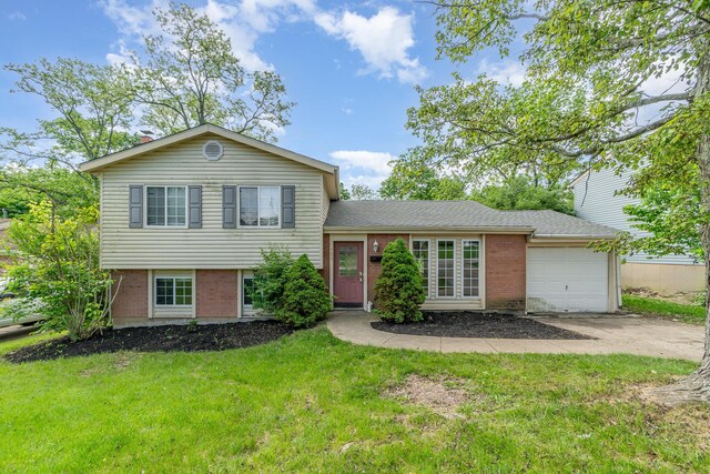 tri-level home featuring a garage, brick siding, driveway, and a front lawn