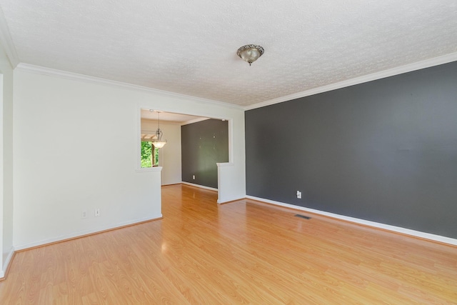 spare room with light wood-type flooring, a textured ceiling, crown molding, and baseboards