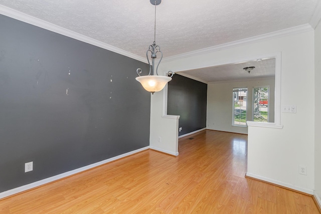 empty room with light wood-style floors, a textured ceiling, baseboards, and crown molding