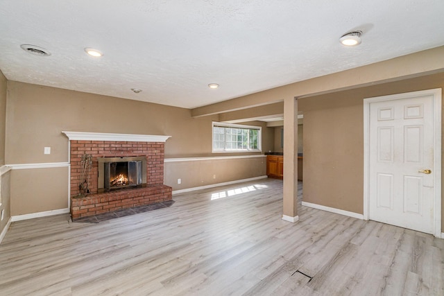 unfurnished living room with light wood-type flooring, baseboards, and a brick fireplace