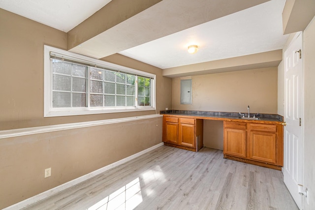 kitchen featuring brown cabinets, light wood-style floors, baseboards, and a sink