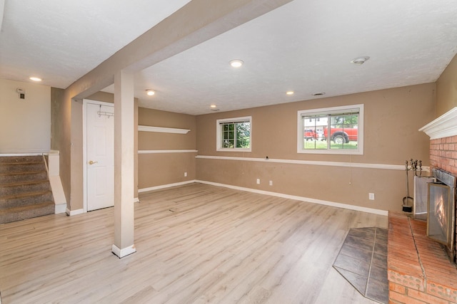 unfurnished living room featuring a fireplace, light wood-type flooring, stairway, baseboards, and recessed lighting