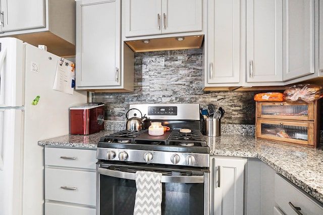 1706 Banklick St, Covington, KY 41011 - kitchen featuring stainless steel range with gas cooktop, decorative backsplash, light stone countertops, freestanding refrigerator, and under cabinet range hood