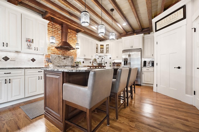 519 Greenup St Unit A, Covington, KY 41011 - kitchen with stainless steel fridge with ice dispenser, wall chimney exhaust hood, glass insert cabinets, wood finished floors, and white cabinets