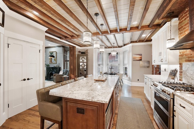 519 Greenup St Unit A, Covington, KY 41011 - kitchen with range with two ovens, wall chimney range hood, beam ceiling, light wood finished floors, and a breakfast bar
