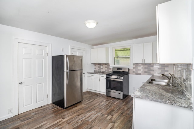 kitchen with stainless steel appliances, a sink, decorative backsplash, white cabinets, and dark wood-type flooring