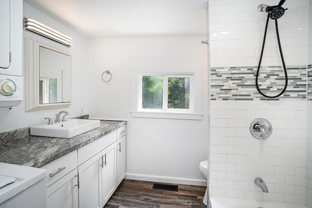 bathroom featuring wood finished floors, toilet, vanity, shower / bathtub combination, and baseboards