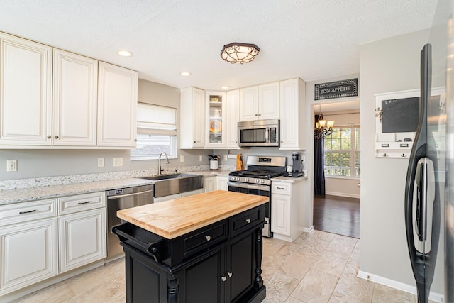 1051 Apple Blossom Dr, Florence, KY 41042 - kitchen with appliances with stainless steel finishes, dark cabinetry, wooden counters, a sink, and white cabinetry