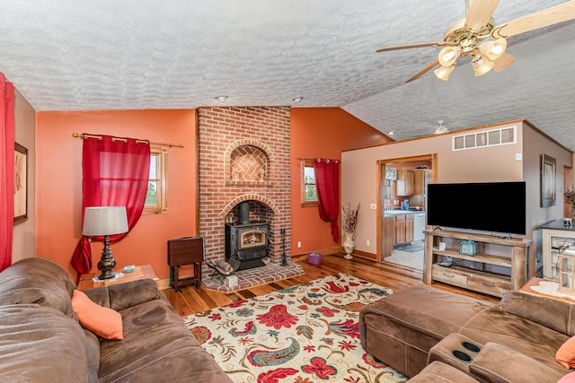 1019 Fisher Rd, Foster, KY 41043 - living room with lofted ceiling, a wood stove, a textured ceiling, a ceiling fan, and wood finished floors