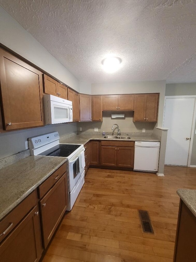 218 Shaker Heights Ln, Crestview Hills, KY 41017 - kitchen featuring white appliances, light wood-type flooring, a textured ceiling, and brown cabinets