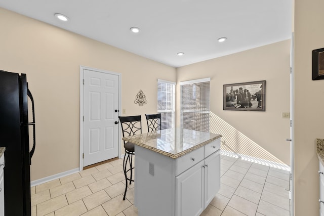 1622 Castle Hill Ln, Fort Wright, KY 41011 - kitchen with freestanding refrigerator, a kitchen breakfast bar, white cabinets, light tile patterned flooring, and baseboards