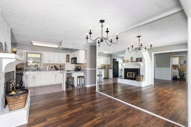510 Jacob Dr, Williamstown, KY 41097 - unfurnished living room featuring a brick fireplace, a chandelier, dark wood finished floors, a textured ceiling, and a sink