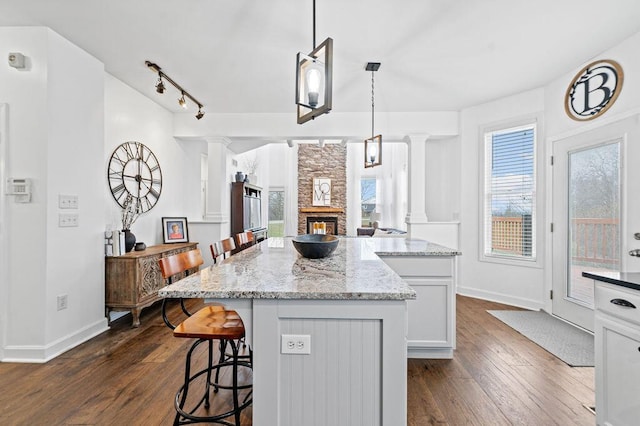 4800 Brewer Ln, Petersburg, KY 41080 - kitchen with ornate columns, a kitchen island, a kitchen bar, a fireplace, and dark wood finished floors