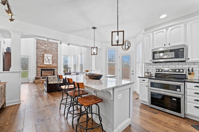4800 Brewer Ln, Petersburg, KY 41080 - kitchen with appliances with stainless steel finishes, white cabinetry, a breakfast bar, ornate columns, and tasteful backsplash