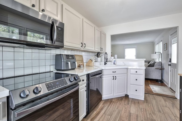 406 Hallam Ave, Erlanger, KY 41018 - kitchen with appliances with stainless steel finishes, a sink, light countertops, a peninsula, and white cabinetry