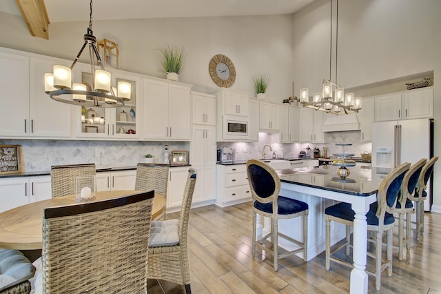 827 Iva Del Ct, Crescent Springs, KY 41017 - kitchen featuring a chandelier, white appliances, dark countertops, a breakfast bar, and a high ceiling