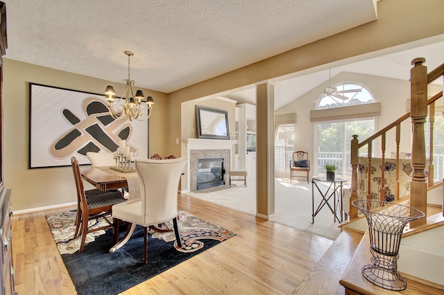 208 Misty Cove Way, Highland Heights, KY 41076 - dining area featuring stairway, light wood-type flooring, a tiled fireplace, vaulted ceiling, and a chandelier