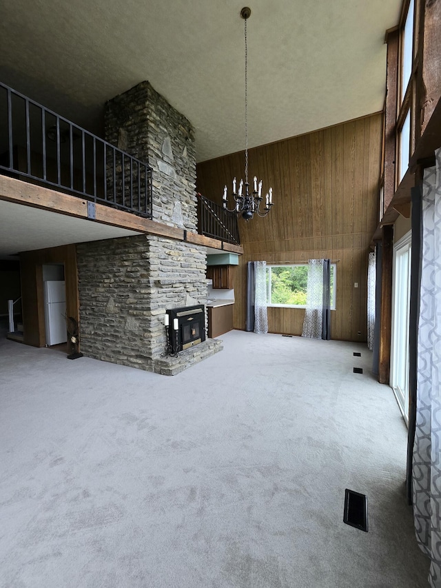 438 Ky Highway 455, Sparta, KY 41086 - unfurnished living room featuring a high ceiling, wooden walls, a fireplace, a chandelier, and carpet