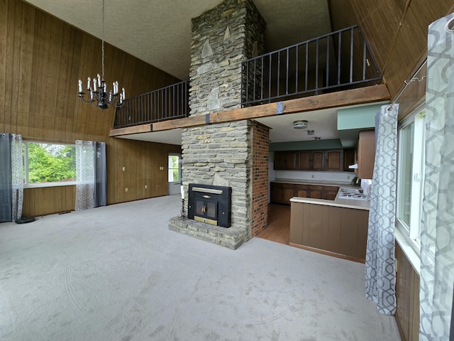 438 Ky Highway 455, Sparta, KY 41086 - unfurnished living room with a high ceiling, wood walls, a chandelier, a fireplace, and carpet floors