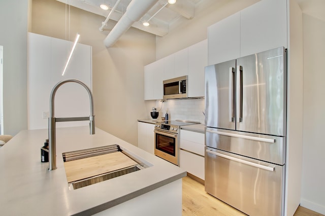 120 Main St Unit 205, Newport, KY 41071 - kitchen featuring appliances with stainless steel finishes, modern cabinets, white cabinetry, tasteful backsplash, and light wood finished floors