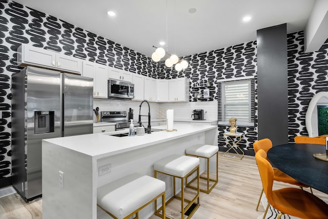 213 8th Ave, Dayton, KY 41074 - kitchen featuring appliances with stainless steel finishes, a sink, light countertops, light wood finished floors, and a kitchen island with sink