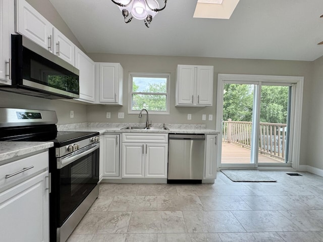 1039 Meadowbrook Ct, Hebron, KY 41048 - kitchen with stainless steel appliances, a sink, a skylight, white cabinetry, and baseboards