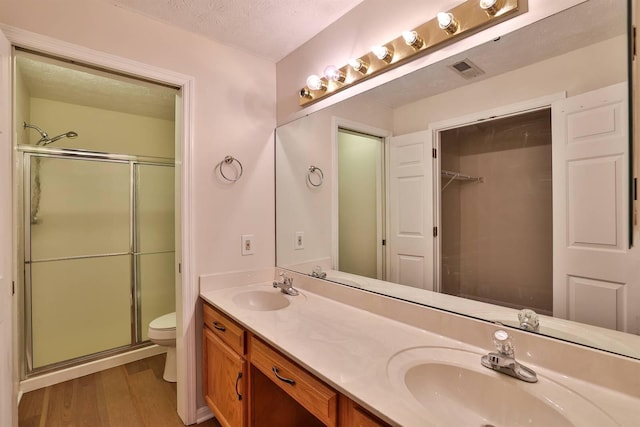 328 Deepwoods Dr, Highland Heights, KY 41076 - bathroom featuring toilet, double vanity, a shower stall, wood finished floors, and a textured ceiling