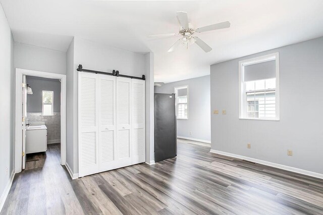 718 Central Ave, Newport, KY 41071 - unfurnished bedroom with a barn door, wood finished floors, multiple windows, and a closet