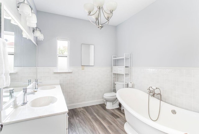 718 Central Ave, Newport, KY 41071 - bathroom with tile walls, a freestanding bath, double vanity, wood finished floors, and a chandelier