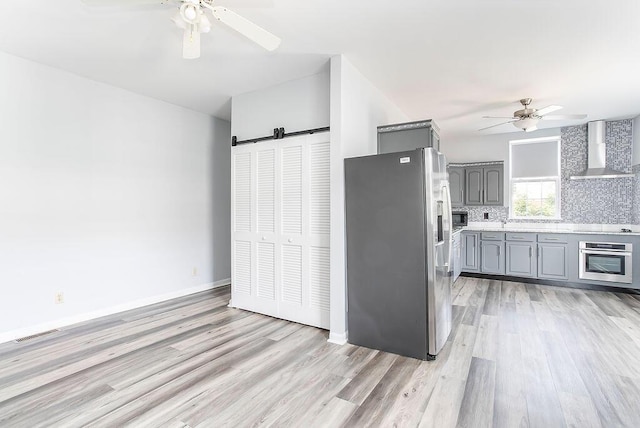 718 Central Ave, Newport, KY 41071 - kitchen featuring appliances with stainless steel finishes, wall chimney exhaust hood, gray cabinetry, a ceiling fan, and a barn door