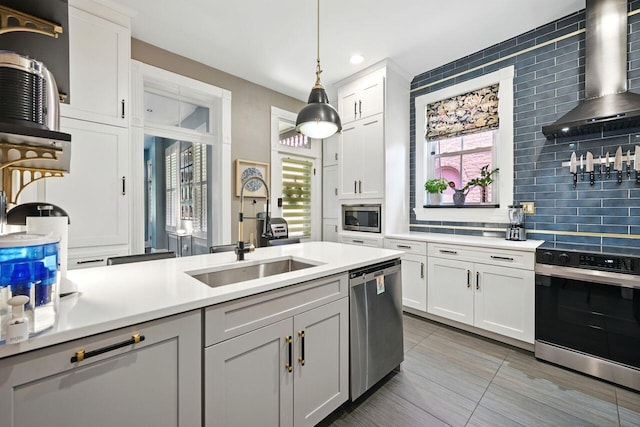 842 Monroe St, Newport, KY 41071 - kitchen with stainless steel appliances, wall chimney exhaust hood, light countertops, tasteful backsplash, and pendant lighting