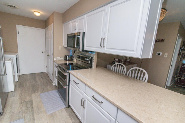 1727 Shaw Rd, Independence, KY 41051 - kitchen with appliances with stainless steel finishes, light wood-type flooring, white cabinetry, light countertops, and washer / dryer