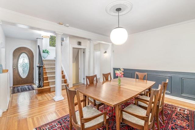 1058 Emerson Rd, Park Hills, KY 41011 - dining area with decorative columns, light wood-style floors, wainscoting, crown molding, and stairs