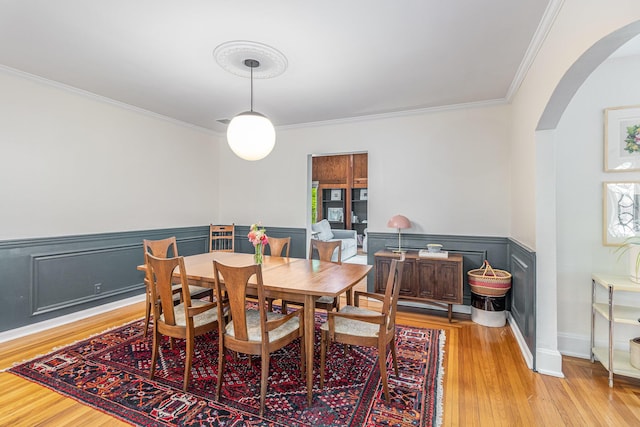 1058 Emerson Rd, Park Hills, KY 41011 - dining space with arched walkways, crown molding, a wainscoted wall, and light wood-style floors