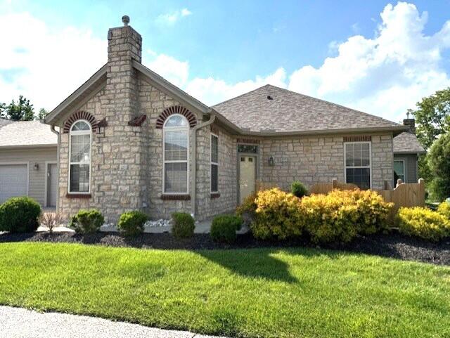9072 Timberbrook Ln Unit B, Florence, KY 41042 - view of front facade with stone siding, a chimney, a front lawn, a garage, and roof with shingles