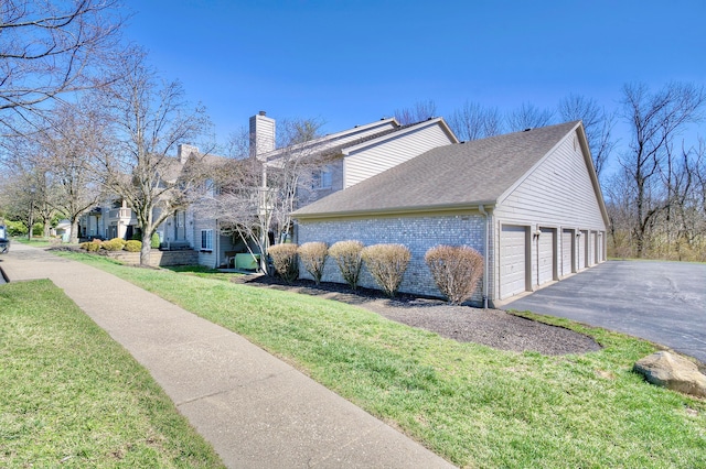 2239 Teal Briar Ln Unit 206, Burlington, KY 41005 - view of home's exterior featuring driveway, a chimney, a yard, brick siding, and a shingled roof