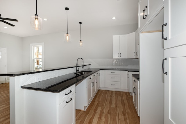 1026 Orchard St, Newport, KY 41071 - kitchen with a sink, a peninsula, light wood-type flooring, white cabinetry, and decorative light fixtures