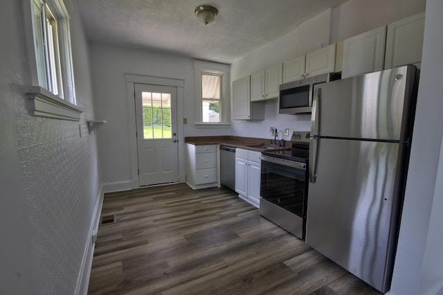 1823 Euclid Ave, Covington, KY 41014 - kitchen with stainless steel appliances, dark wood-style floors, dark countertops, a sink, and white cabinets