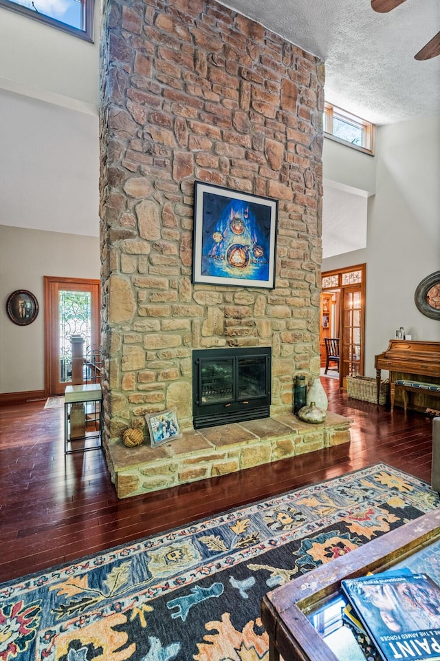 2709 Longbranch Rd, Union, KY 41091 - living area featuring wood-type flooring, a stone fireplace, a textured ceiling, a ceiling fan, and baseboards