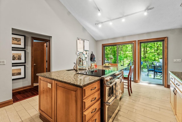 2709 Longbranch Rd, Union, KY 41091 - kitchen featuring double oven range, brown cabinets, a center island with sink, dark stone counters, and lofted ceiling