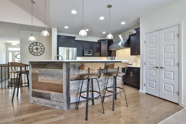 6520 Cannondale Dr, Burlington, KY 41005 - kitchen with stainless steel appliances, wall chimney exhaust hood, tasteful backsplash, light countertops, and light wood-style flooring