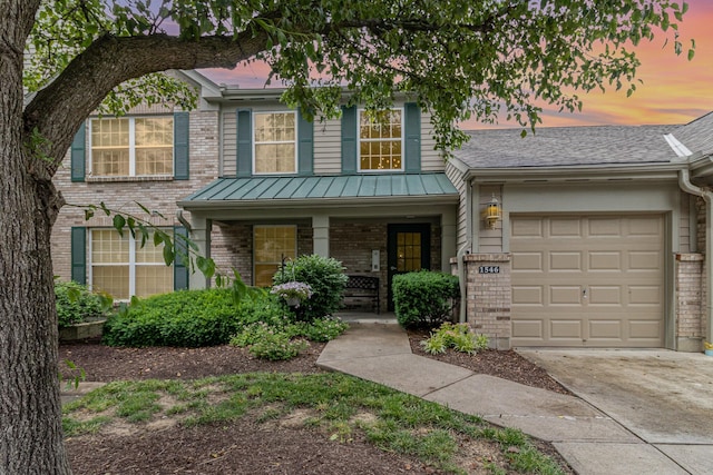 1546 Taramore Dr Unit 203, Florence, KY 41042 - view of front of property featuring brick siding, covered porch, concrete driveway, an attached garage, and a standing seam roof