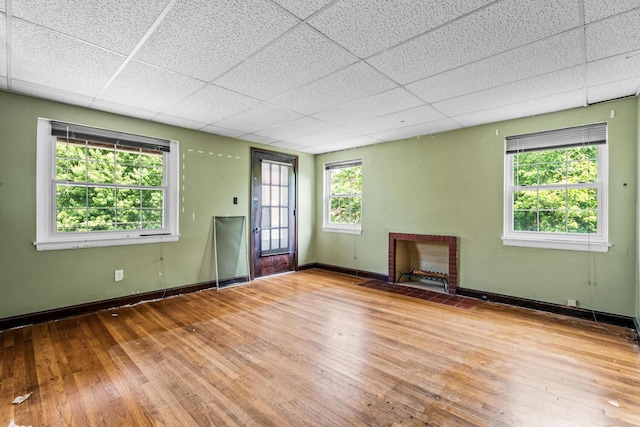 309 Hawthorne St, Covington, KY 41014 - empty room with hardwood / wood-style floors, a drop ceiling, baseboards, and a brick fireplace