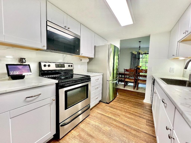 202 Shaker Heights Ln, Crestview Hills, KY 41017 - kitchen with appliances with stainless steel finishes, a sink, light wood-type flooring, white cabinets, and light stone counters