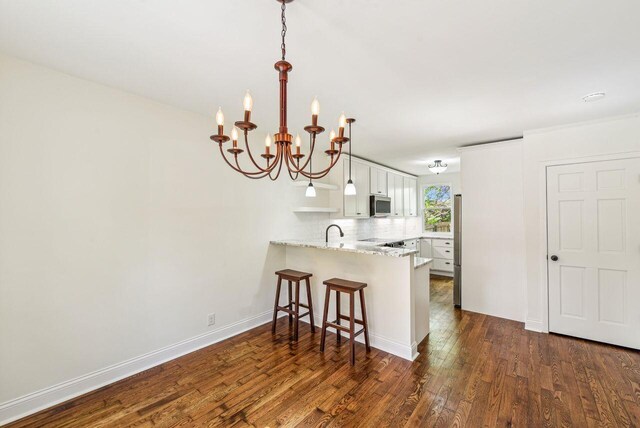 831 Linden Ave, Newport, KY 41071 - kitchen with stainless steel appliances, a peninsula, a chandelier, dark wood finished floors, and a breakfast bar area